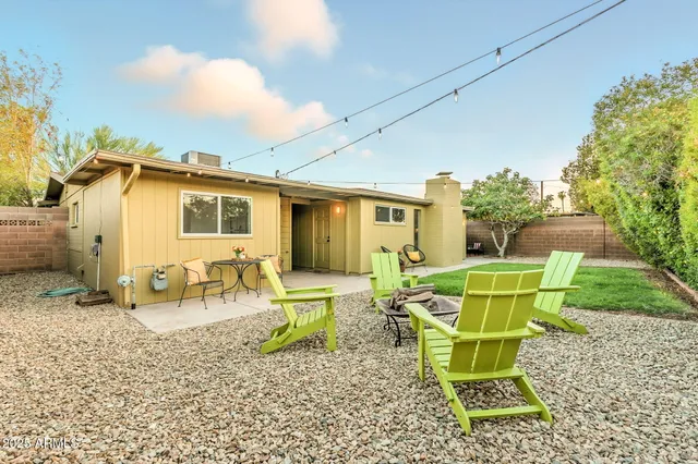 a backyard of a house with table and chairs plants and large trees