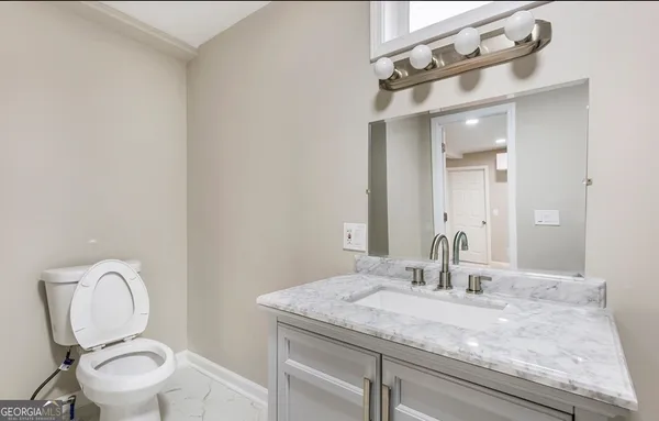 a bathroom with a granite countertop toilet sink and mirror