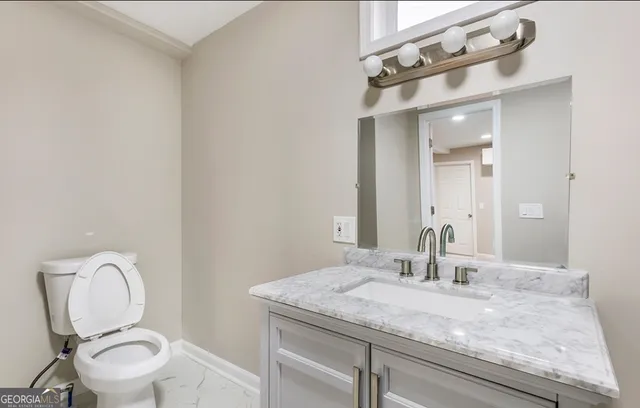 a bathroom with a granite countertop toilet sink and mirror