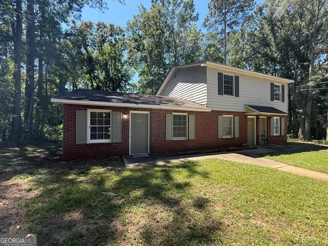 a front view of a house with yard and trees
