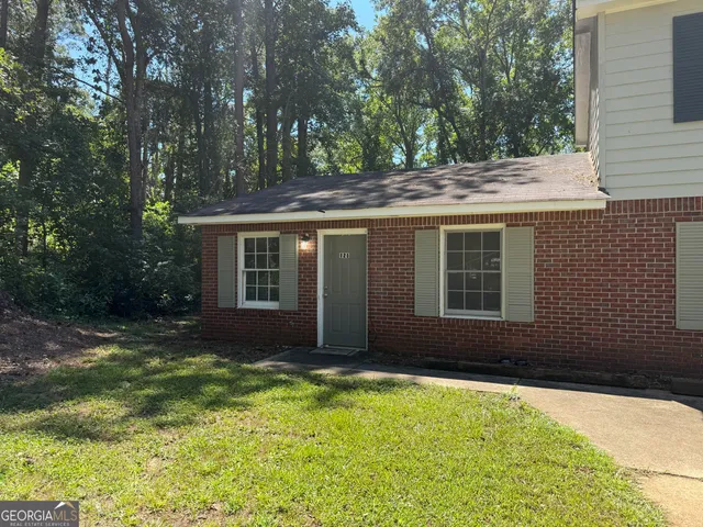 a backyard of a house with large trees and plants