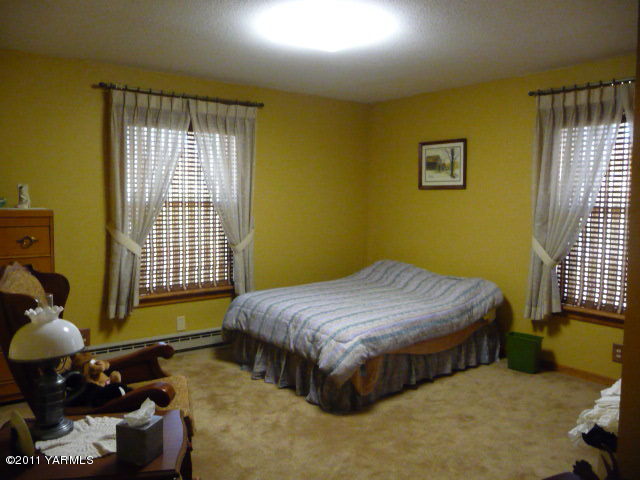 9810 Mieras Road Yakima, WA 98901 - Photo 8 of 16 a bedroom with a bed mirror and window