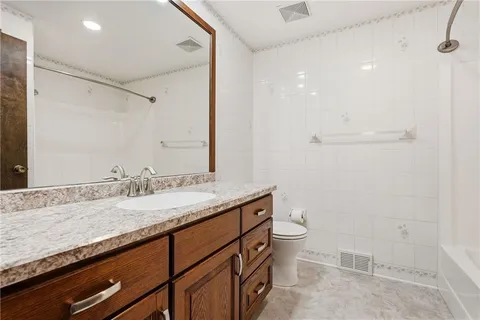 a bathroom with a granite countertop sink a toilet and a mirror