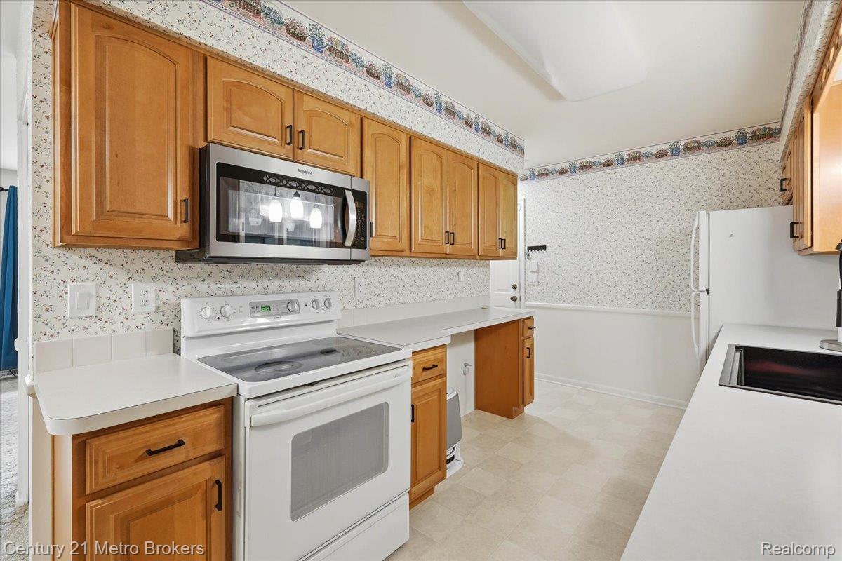 5457 North Seymour Road Flushing, MI 48433 - Photo 20 of 43 Kitchen with light flooring, wallpapered walls, white appliances, light countertops, and wood finish cabinetry