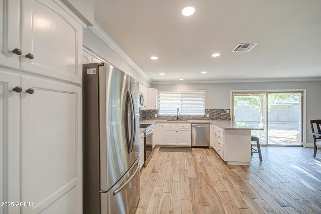 a kitchen with a refrigerator and white cabinets with wooden floor