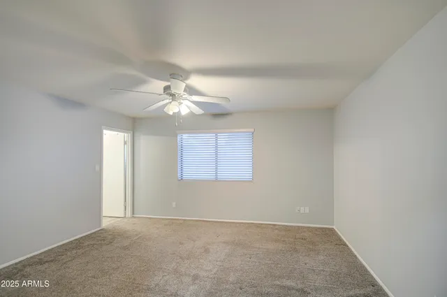 an empty room with a chandelier fan and windows