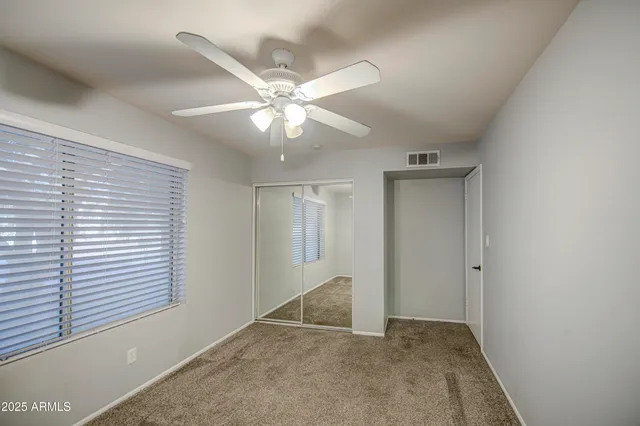 an empty room with windows and fan