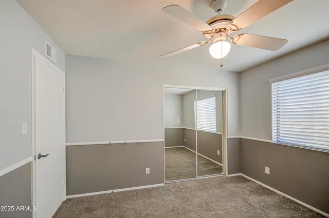 an empty room with windows and fan