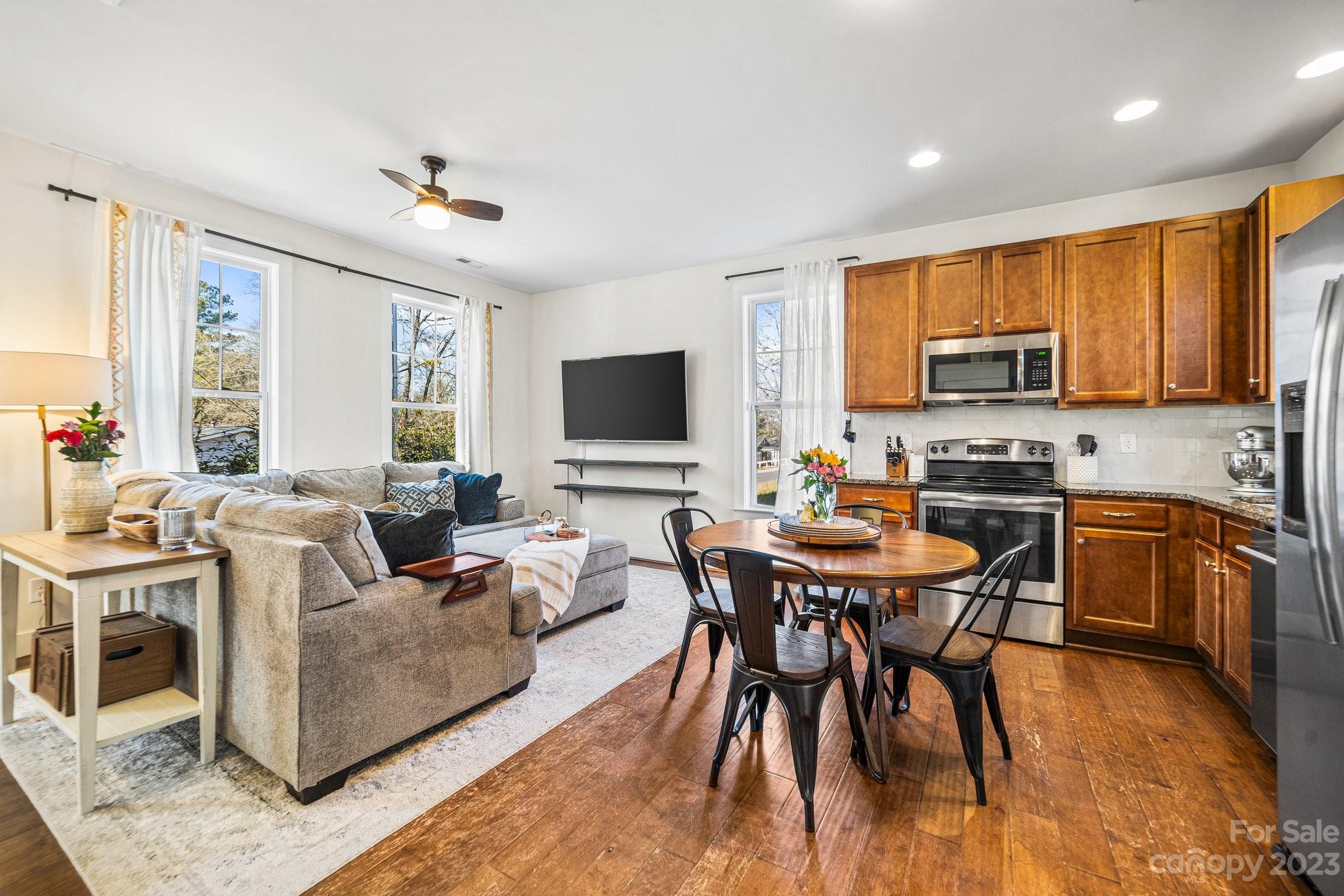 152 Mock Road Davidson, NC 28036 - Photo 7 of 29 a living room with a couch a dining table and a flat screen tv with wooden floor