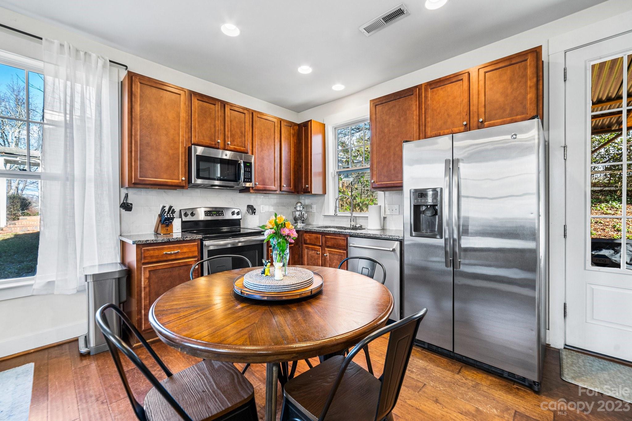 152 Mock Road Davidson, NC 28036 - Photo 9 of 29 a kitchen with stainless steel appliances granite countertop a stove a refrigerator a microwave a sink and a dining table with wooden cabinet