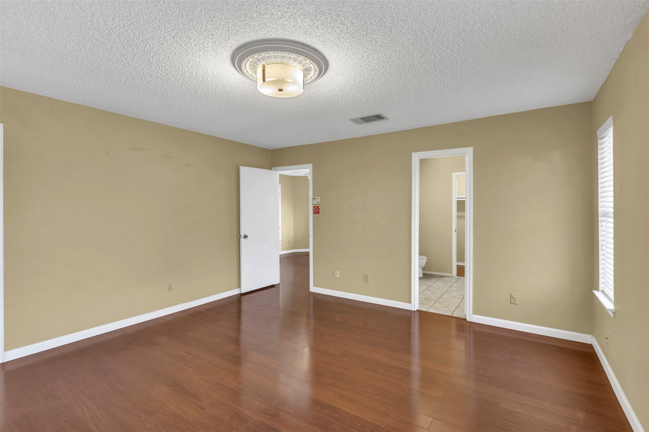 12922 Marimba Trail Austin, TX 78729 - Photo 11 of 28 Unfurnished bedroom featuring dark wood-style floors and a textured ceiling