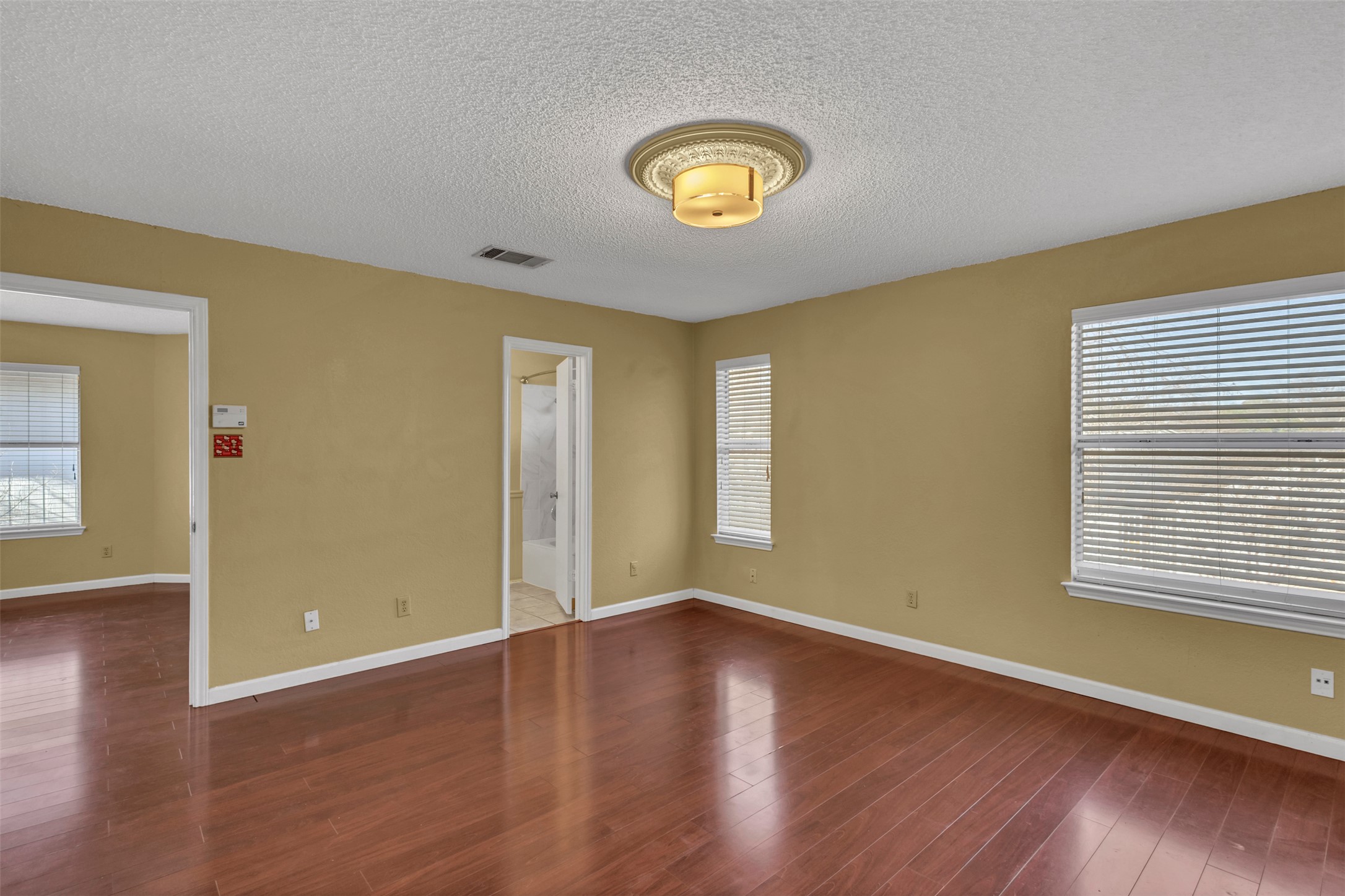 12922 Marimba Trail Austin, TX 78729 - Photo 12 of 28 Unfurnished room featuring wood finished floors and a textured ceiling