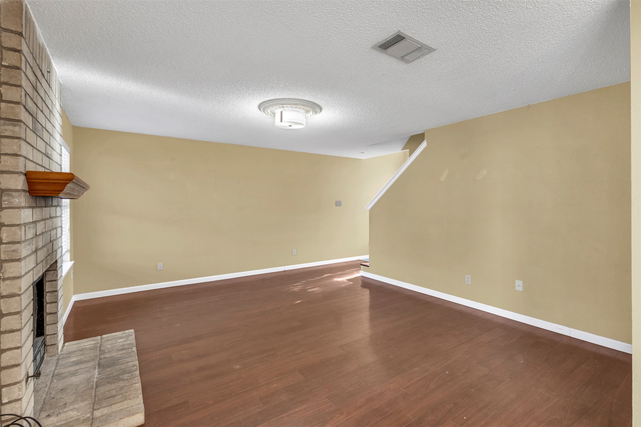 12922 Marimba Trail Austin, TX 78729 - Photo 6 of 28 Unfurnished living room with dark wood-style flooring, a textured ceiling, and a fireplace