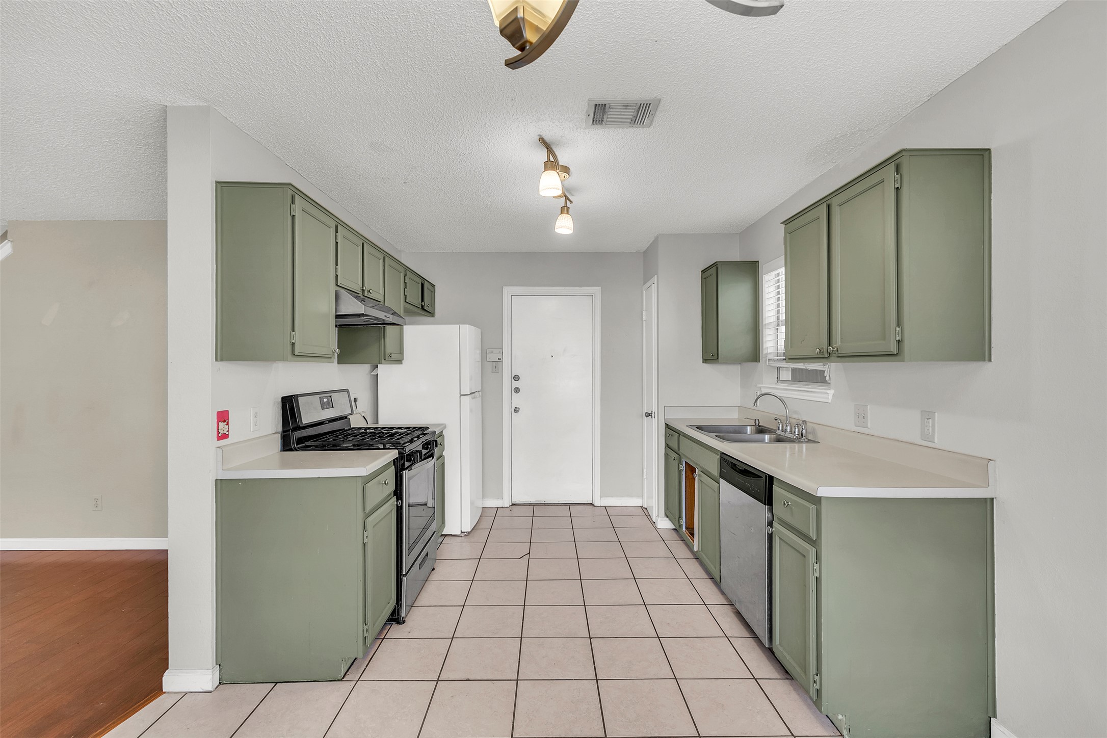 12922 Marimba Trail Austin, TX 78729 - Photo 7 of 28 Kitchen with green cabinetry, light countertops, stainless steel appliances, and a textured ceiling