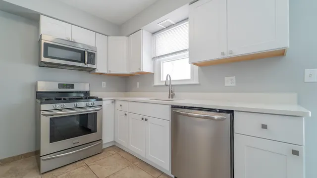 a kitchen with stainless steel appliances granite countertop a sink a stove a microwave and wooden cabinets