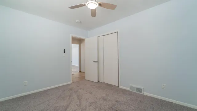 an empty room with a chandelier fan and a ceiling fan