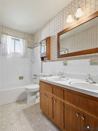 a bathroom with a double vanity sink a toilet and a bathtub