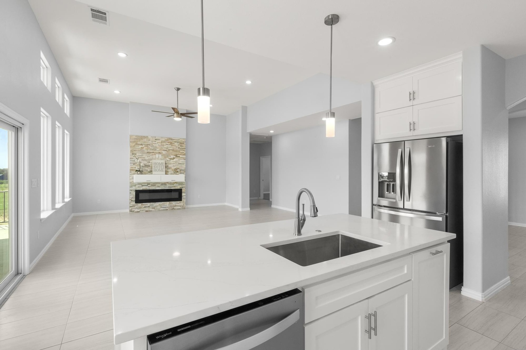 1136 County Road 484 Elgin, TX 78621 - Photo 13 of 37 Kitchen featuring white cabinetry, stainless steel dishwasher, light tile patterned floors, an island with sink, and decorative light fixtures