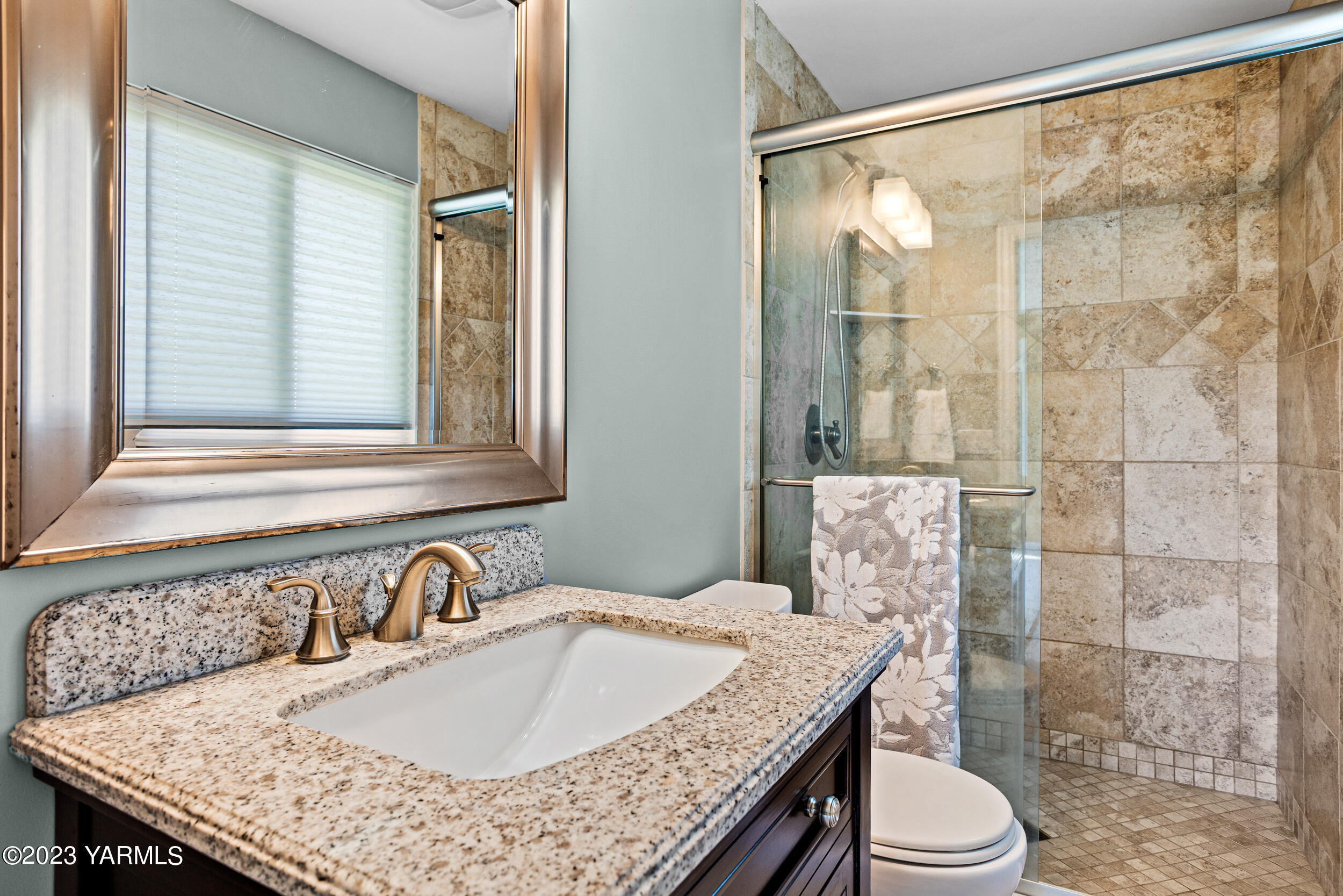 13518 Fisk Road Yakima, WA 98908 - Photo 22 of 58 a bathroom with a granite countertop sink a toilet a mirror and shower