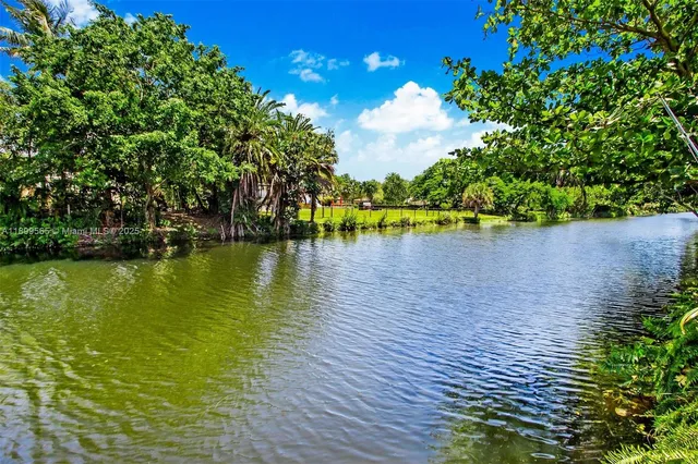 a kitchen with stainless steel appliances granite countertop a refrigerator a sink dishwasher a stove a refrigerator and a dining table with wooden floor