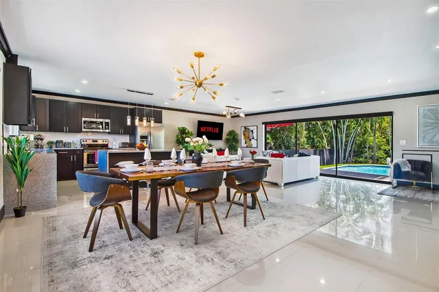 a view of a dining room with furniture a chandelier and large windows