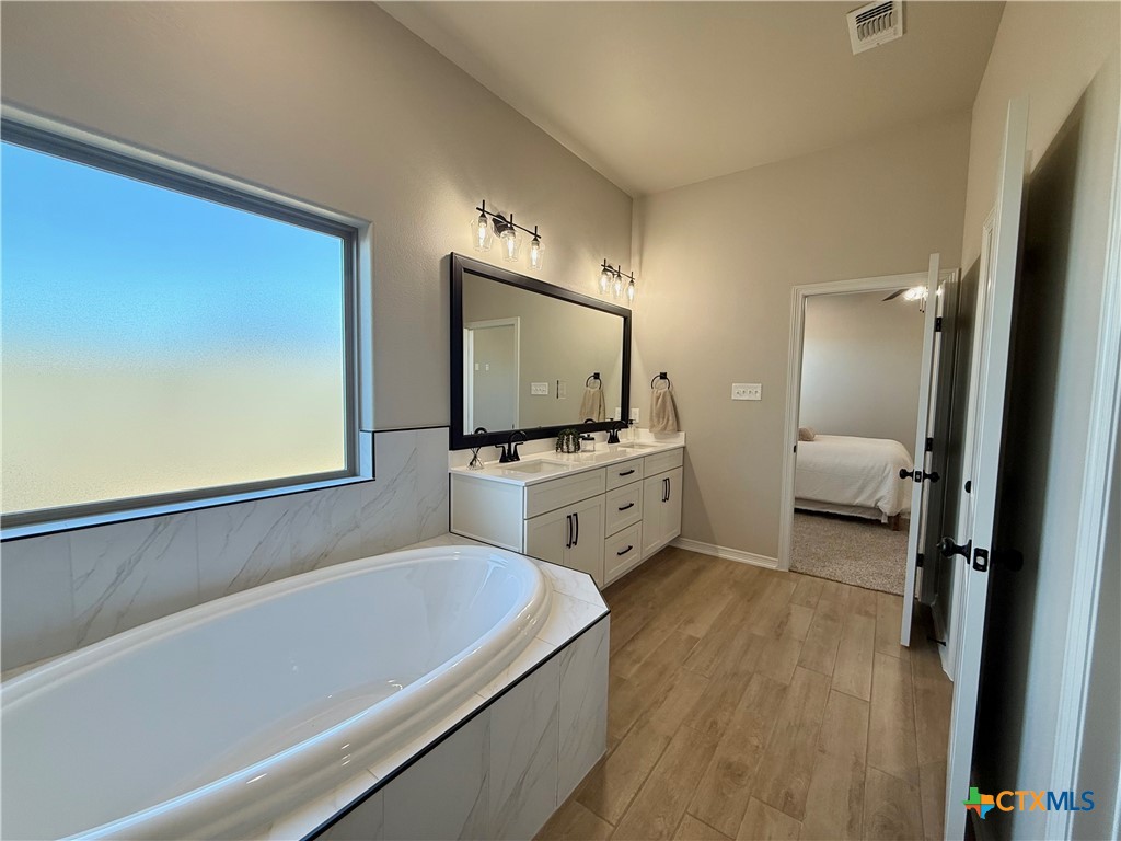 203 Lasso Loop Lorena, TX 76655 - Photo 30 of 36 a en suite bathroom with a double vanity sink a mirror and a bathtub