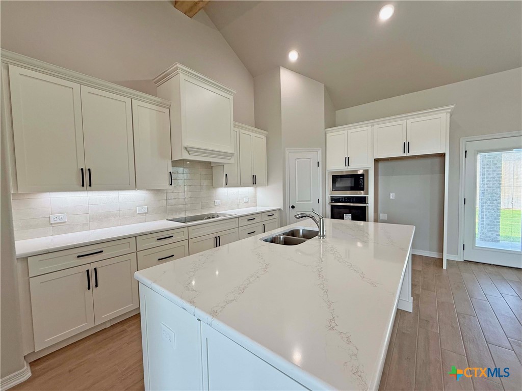 203 Lasso Loop Lorena, TX 76655 - Photo 7 of 24 a kitchen with a sink a stove a refrigerator and white cabinets