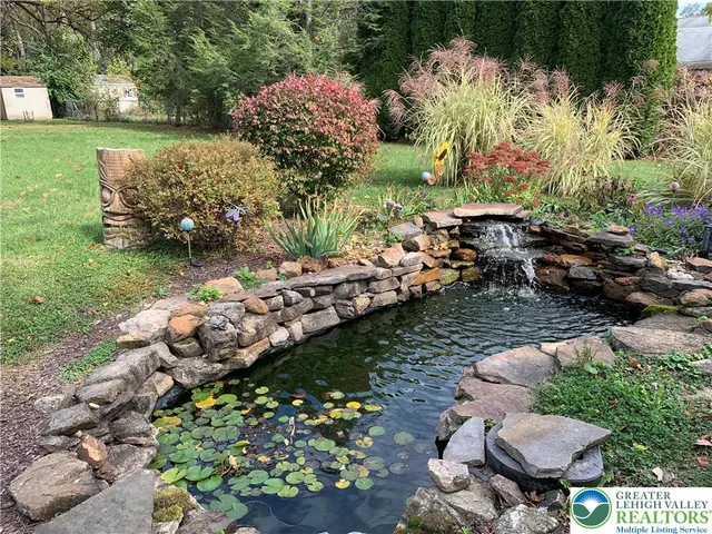 a garden with lots of trees and flowers and covered with wooden fence