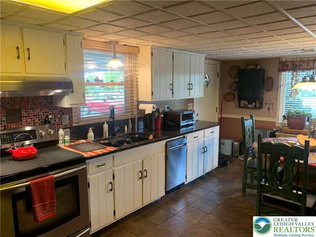 a kitchen with stainless steel appliances a sink dishwasher stove and white cabinets