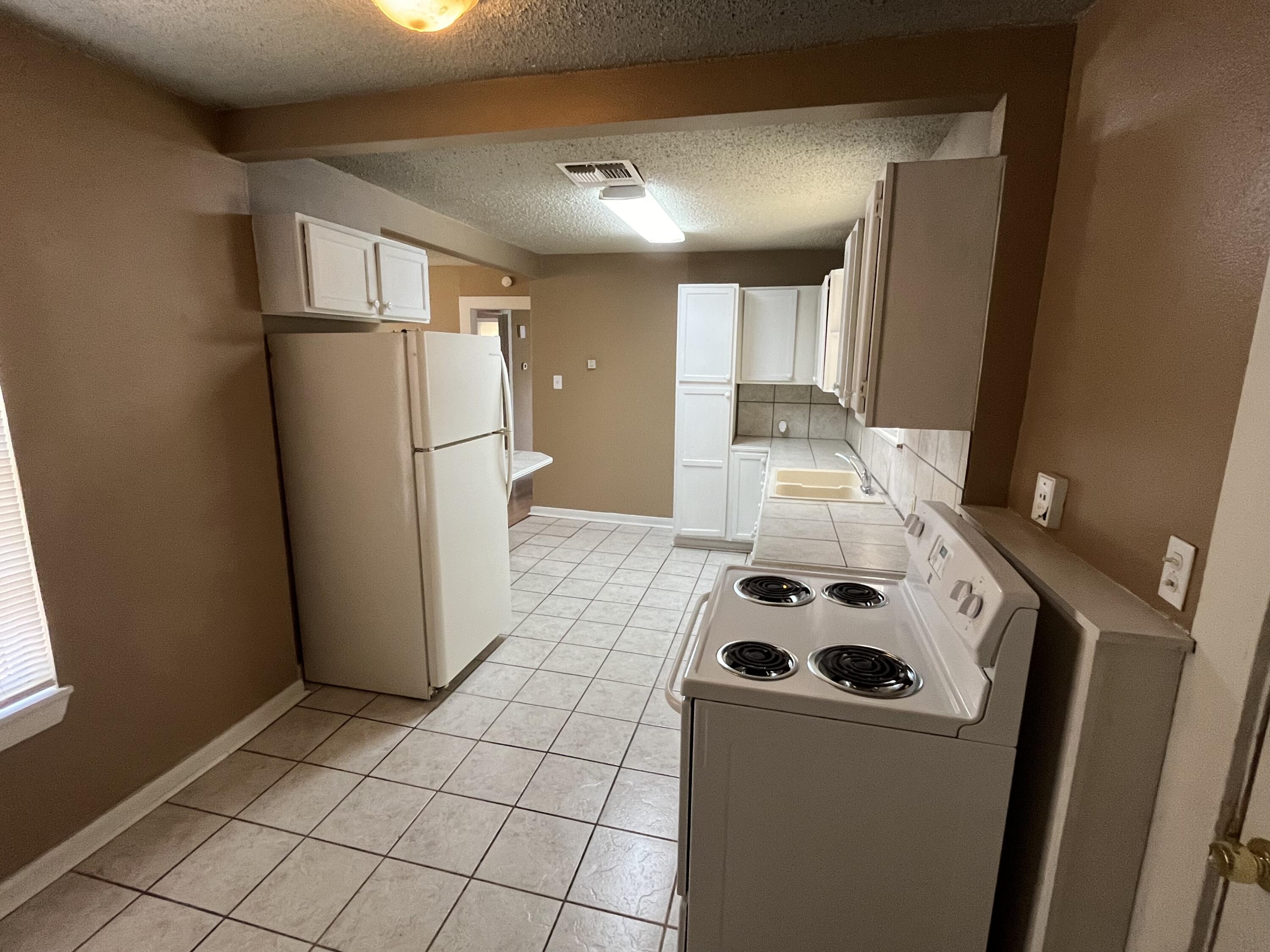 2111 25th Street Lubbock, TX 79411 - Photo 3 of 8 a kitchen with a refrigerator and a stove top oven