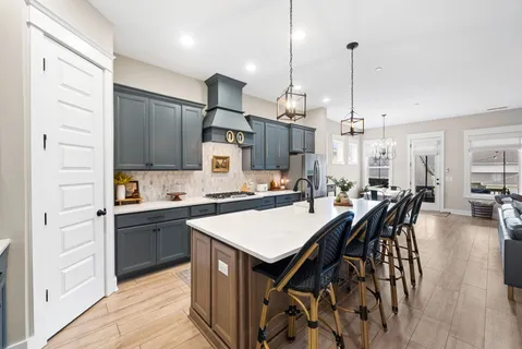 a kitchen with stainless steel appliances granite countertop a stove a refrigerator a kitchen island a dining table and chairs with wooden floor