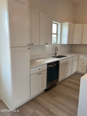 a kitchen with a sink dishwasher a stove and white cabinets