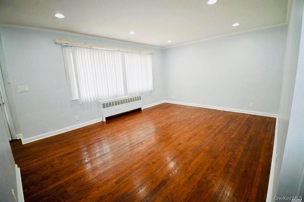 241 Woodbury Road Hicksville, NY 11801 - Photo 6 of 13 an empty room with wooden floor and windows