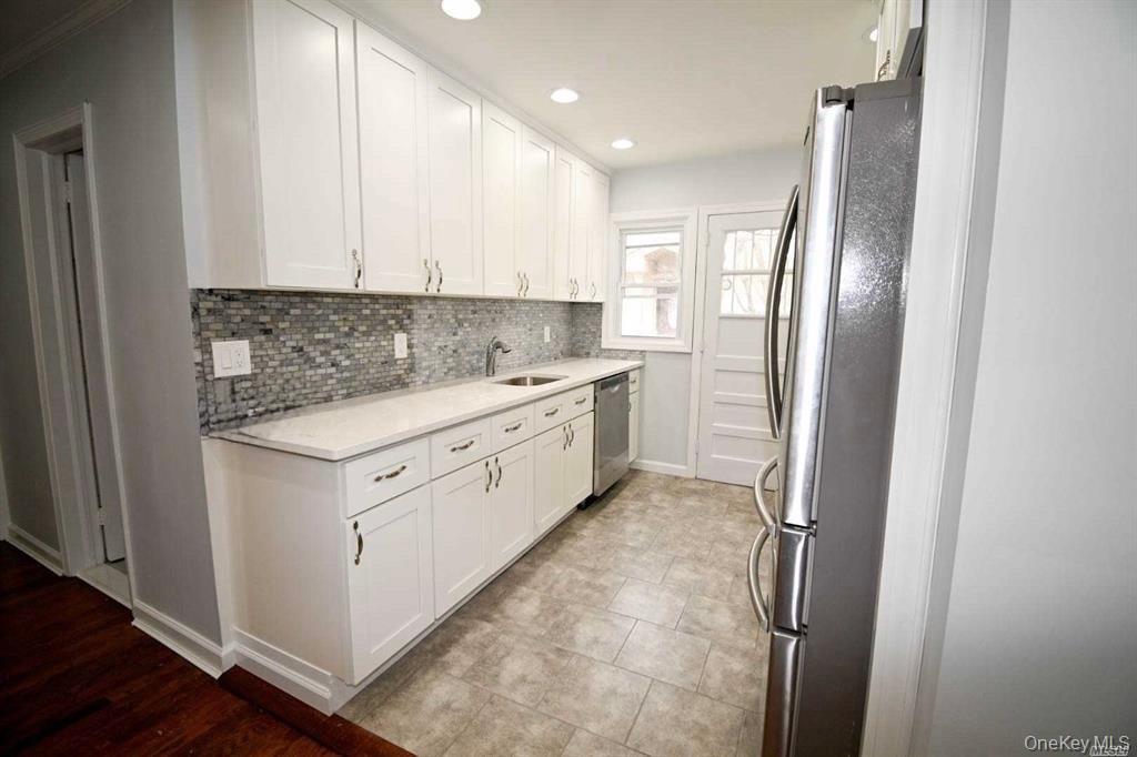 241 Woodbury Road Hicksville, NY 11801 - Photo 8 of 13 a kitchen with a refrigerator sink and cabinets