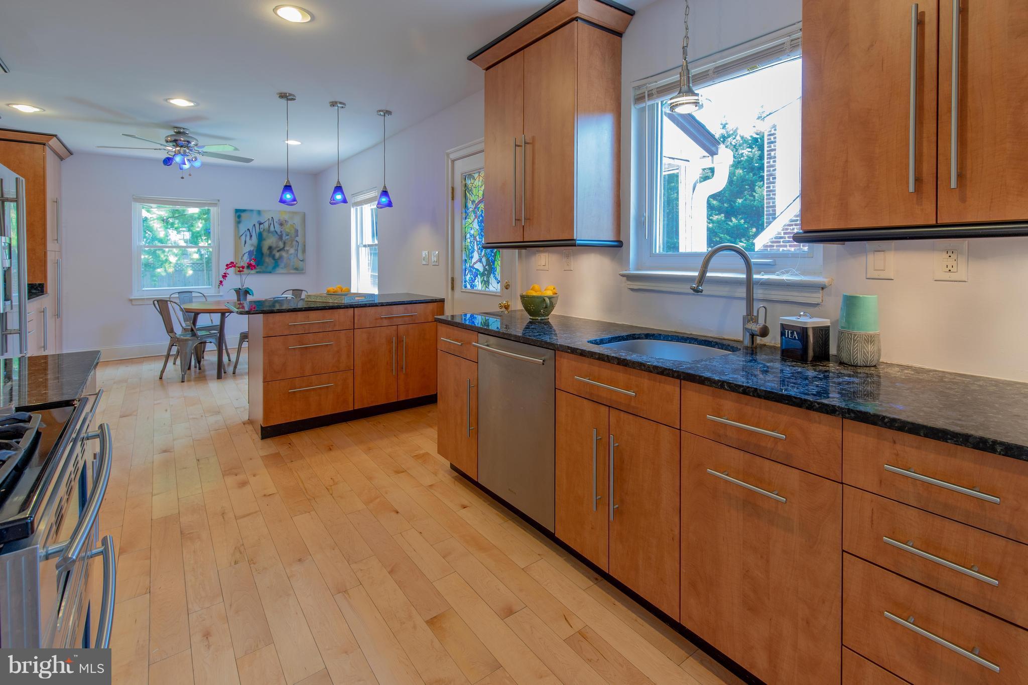 9940 Moss Avenue Silver Spring, MD 20901 - Photo 12 of 30 a kitchen with stainless steel appliances granite countertop wooden cabinets a sink a stove a dining table and chairs