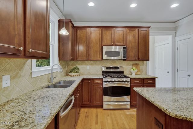 a kitchen with stainless steel appliances granite countertop a stove a sink and a microwave