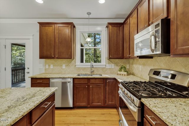 a kitchen with stainless steel appliances granite countertop a stove a sink dishwasher and cabinets with wooden floor