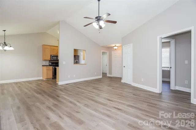 a view of an empty room with wooden floor and a ceiling fan