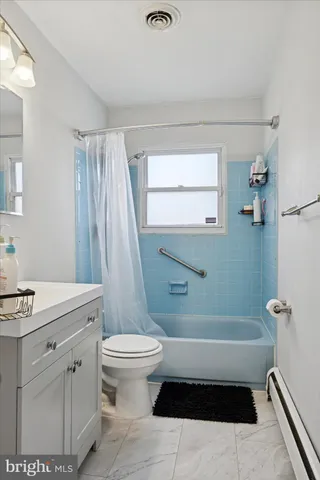 a bathroom with a sink a toilet a window and shower