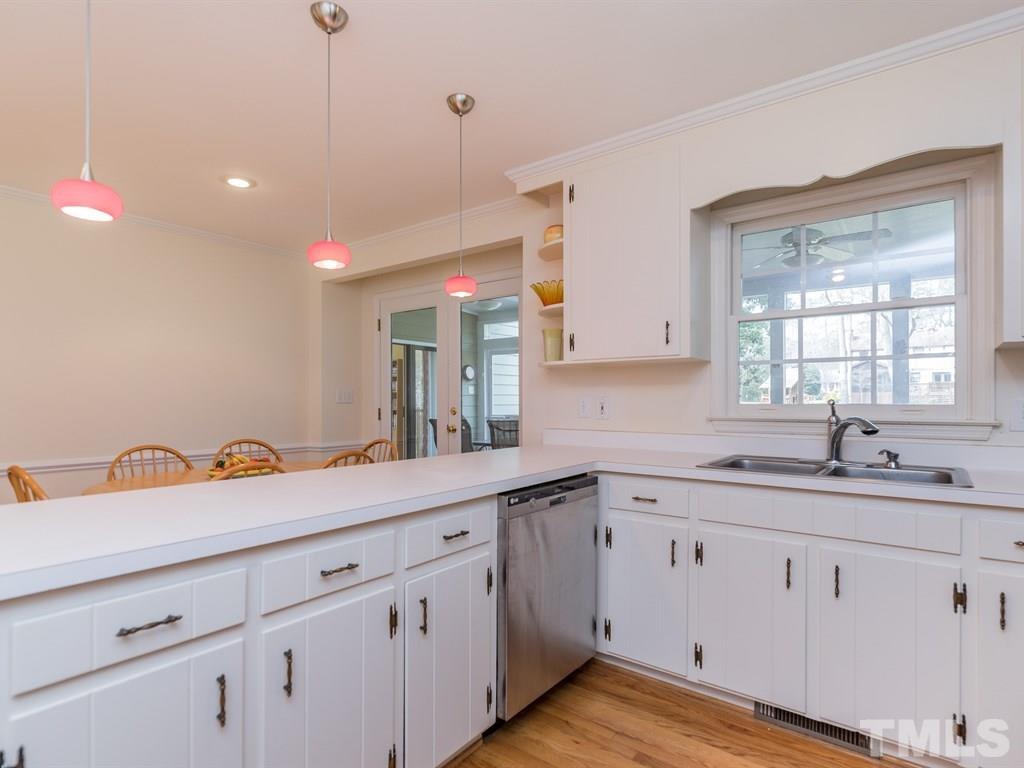 1213 Hunting Ridge Road Raleigh, NC 27615 - Photo 9 of 25 a kitchen with a sink dishwasher and white cabinets with wooden floor