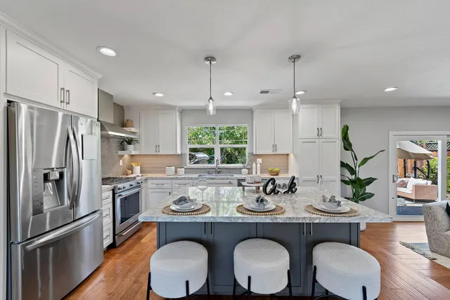a kitchen with sink a refrigerator and chairs