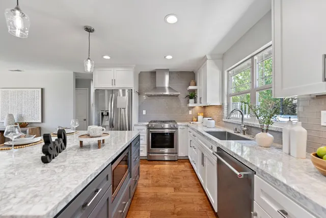 a kitchen with kitchen island granite countertop a large counter top space a sink stainless steel appliances and windows