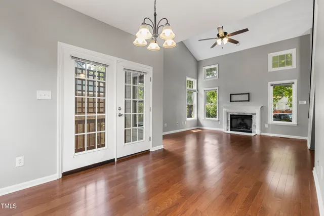 an empty room with wooden floor fireplace and windows