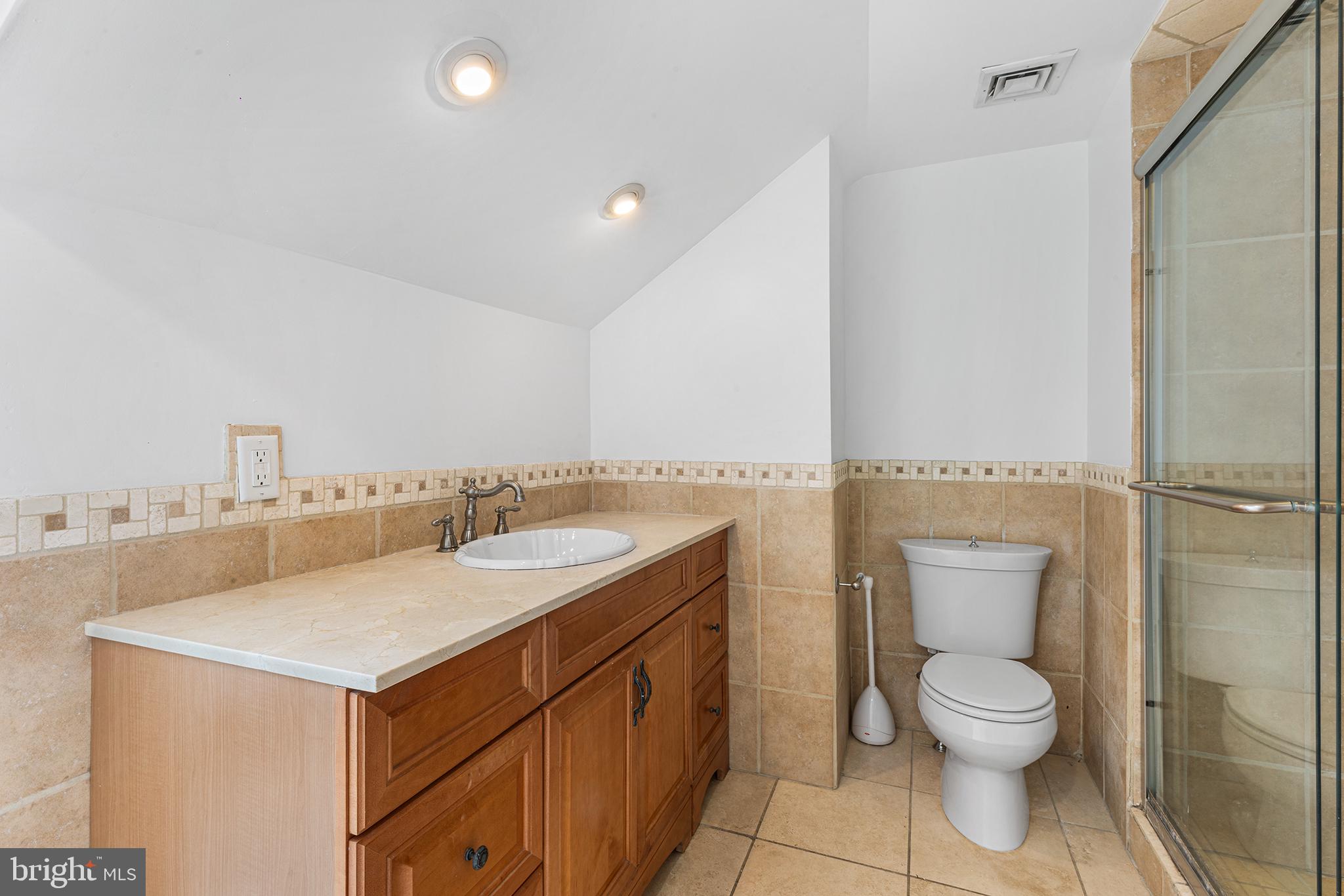 902 Pine Street, Unit 3F Philadelphia, PA 19107 - Photo 16 of 22 a bathroom with a granite countertop toilet a sink and a mirror