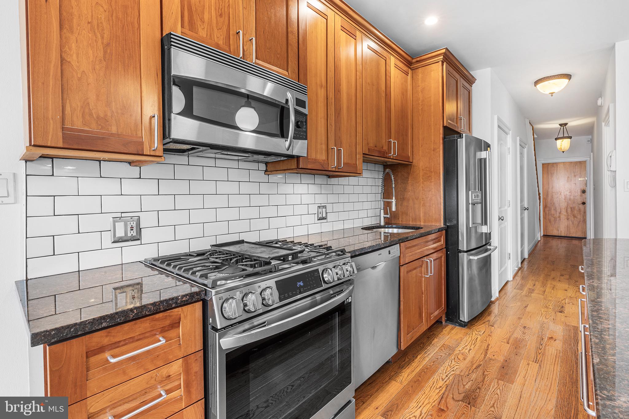 902 Pine Street, Unit 3F Philadelphia, PA 19107 - Photo 5 of 22 a kitchen with stainless steel appliances granite countertop a stove a microwave and a refrigerator