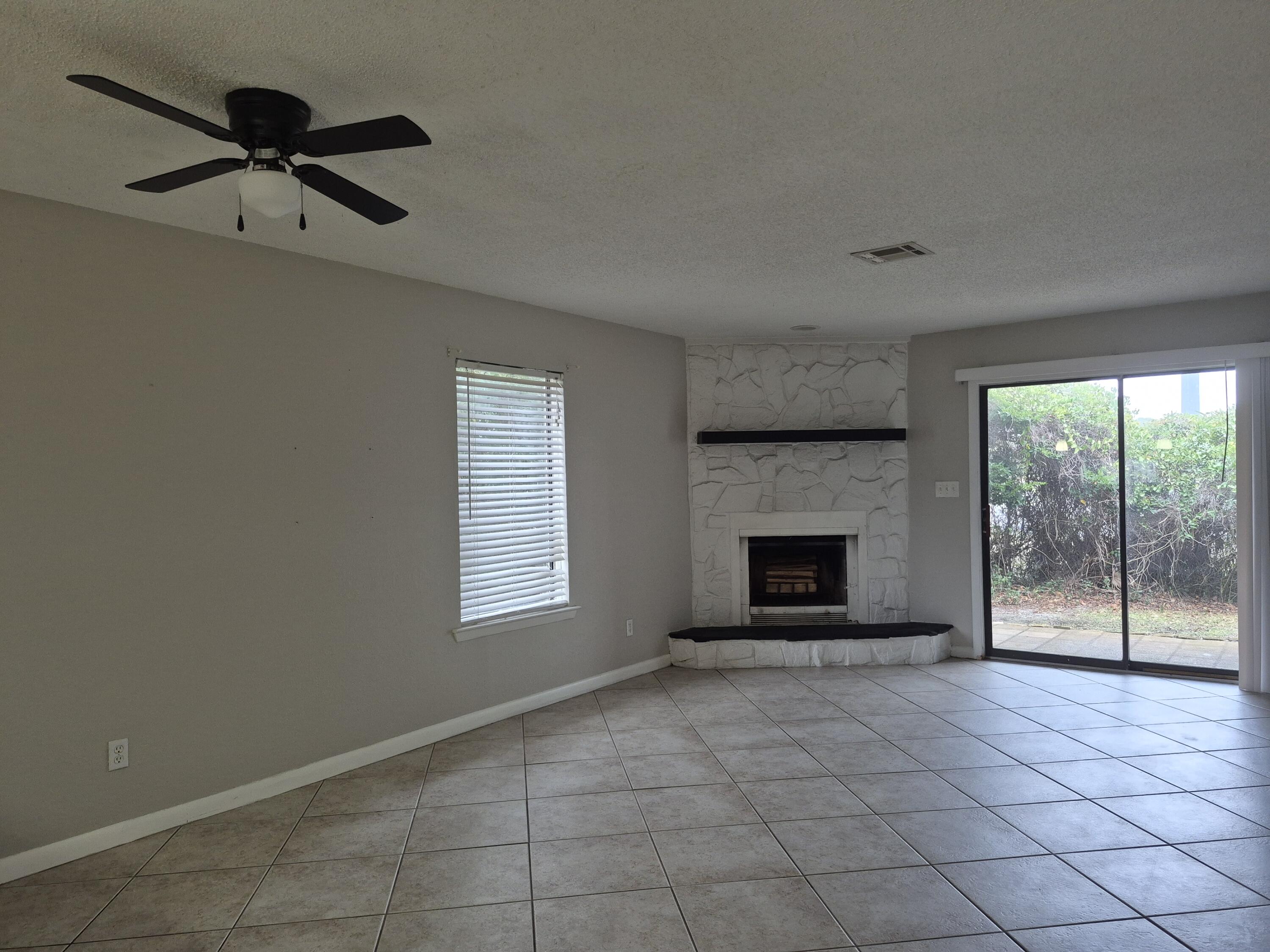 26 Court Destin, Unit 26 Destin, FL 32541 - Photo 3 of 14 a living room with a fireplace and a floor to ceiling window