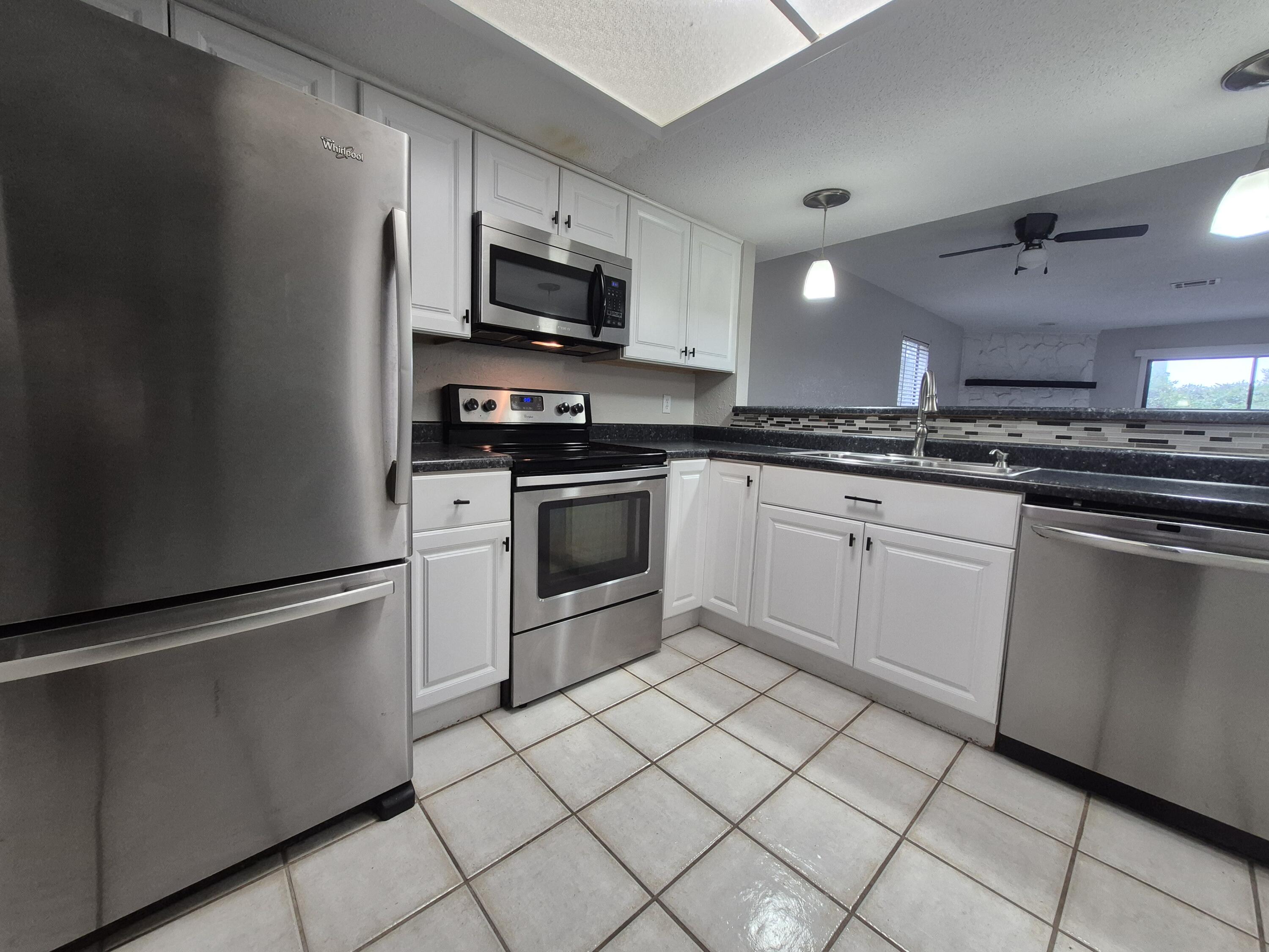 26 Court Destin, Unit 26 Destin, FL 32541 - Photo 5 of 14 a kitchen with white cabinets stainless steel appliances and sink