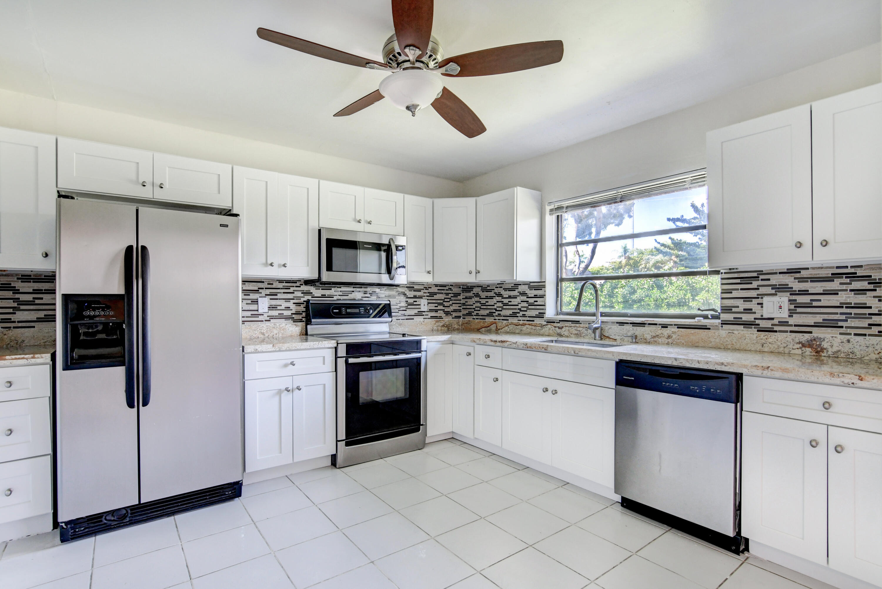 4867 Hawkwood Road, Unit B Boynton Beach, FL 33436 - Photo 12 of 37 a kitchen with granite countertop white cabinets stainless steel appliances a sink and a window