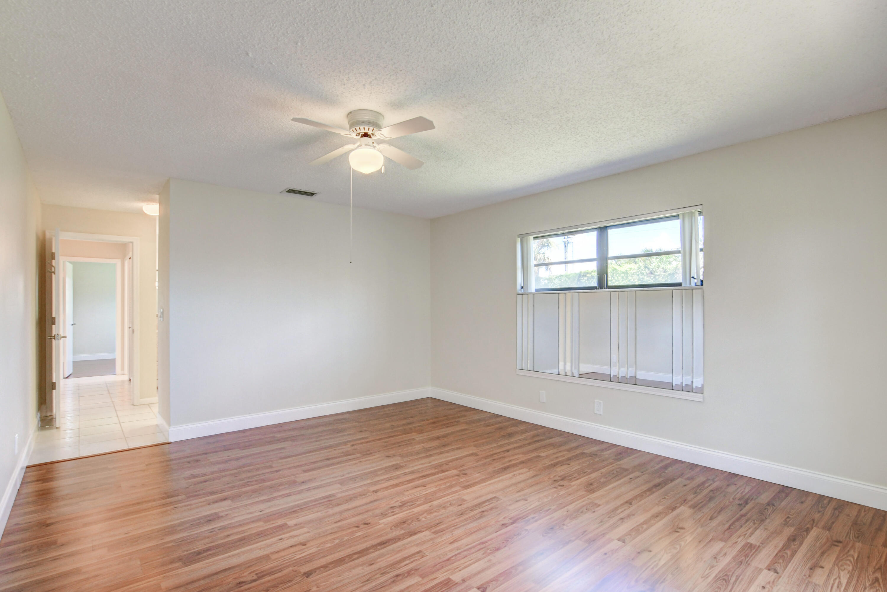 4867 Hawkwood Road, Unit B Boynton Beach, FL 33436 - Photo 17 of 37 an empty room with wooden floor fan and windows