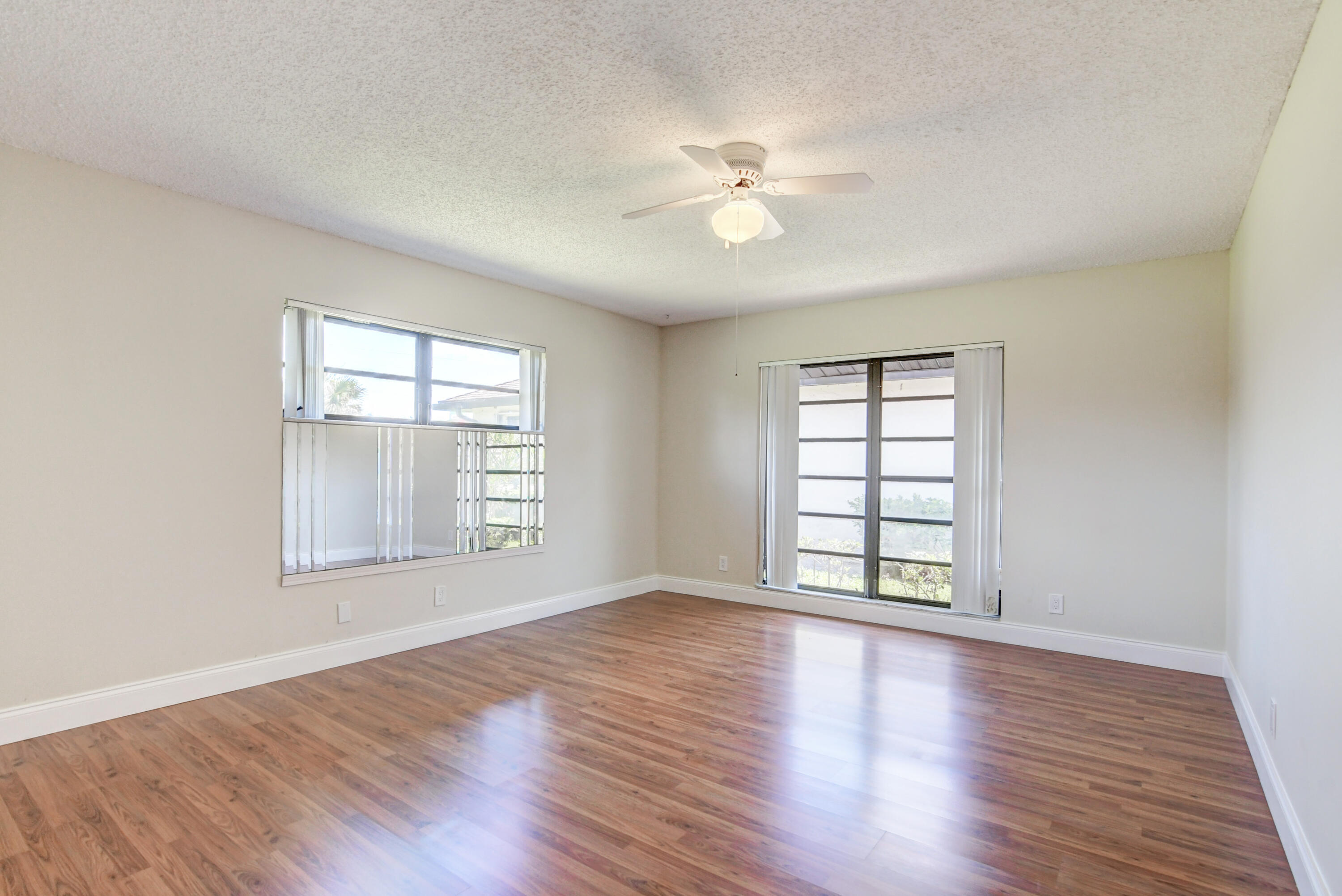 4867 Hawkwood Road, Unit B Boynton Beach, FL 33436 - Photo 18 of 37 an empty room with wooden floor chandelier fan and windows